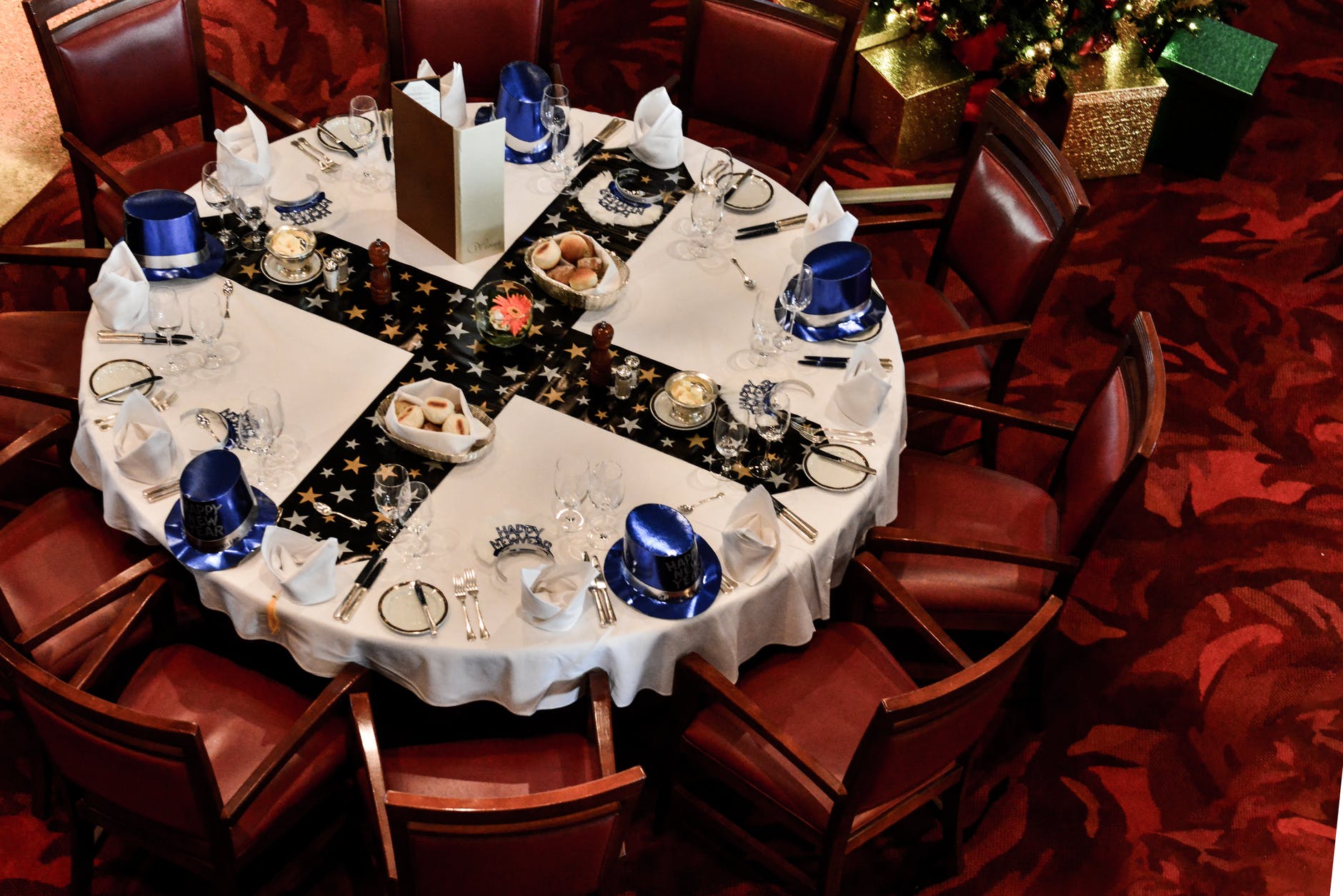 Elegantly set round dining table with festive decorations and blue-themed place settings.