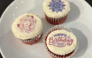 Three frosted cupcakes with decorative edible custom bat or bar mitzvah logos.