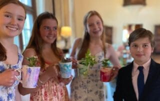 Four young people smiling and holding decorative cups with plants inside. These were bat mitzvah party favors.